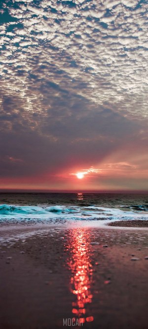 Sunset over the ocean with colorful clouds and beach