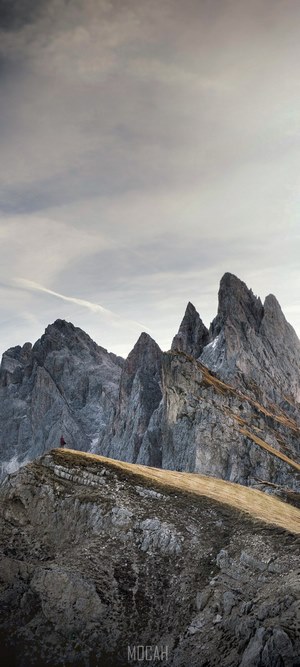 Person on mountain ridge overlooking jagged peaks