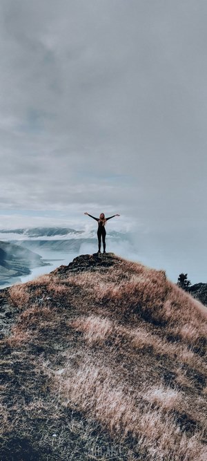 Woman on cliff overlooking a foggy landscape