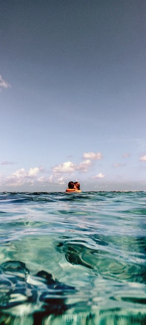 Couple hugging in the ocean with blue sky