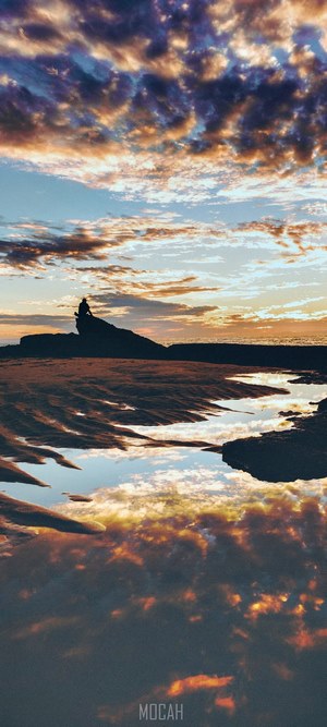 Silhouette of a person on a rock at sunset