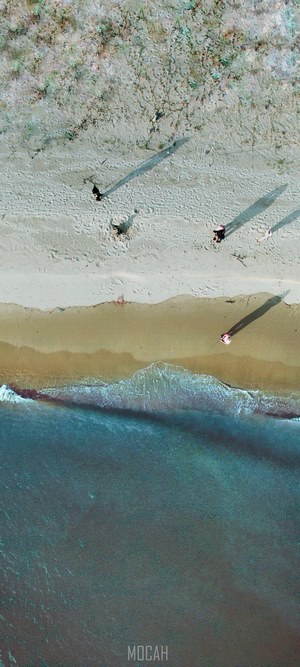 Aerial view of people walking on a sandy beach near the ocean