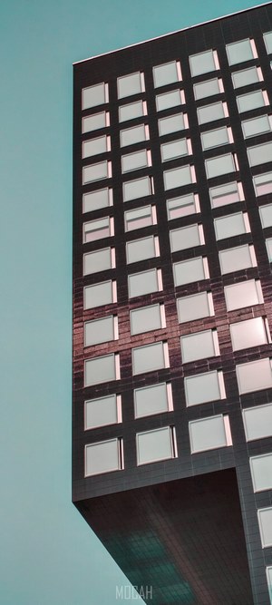 Modern skyscraper with many windows against a teal sky