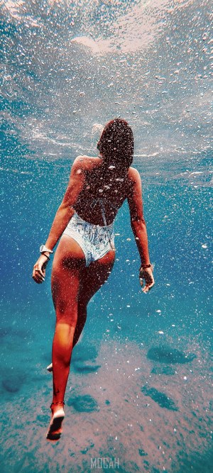 Woman swimming underwater with bubbles