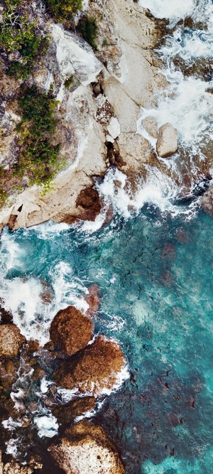 Aerial view of rocky coastline and turquoise ocean waves