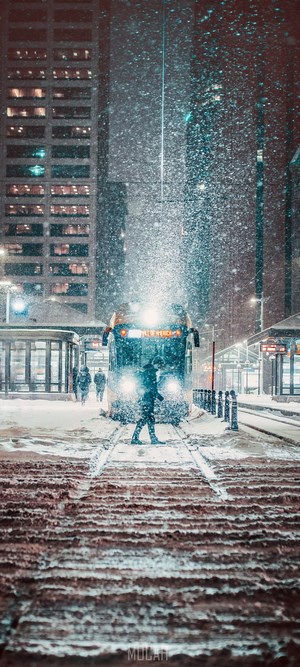 Person walking in snow towards a train at night