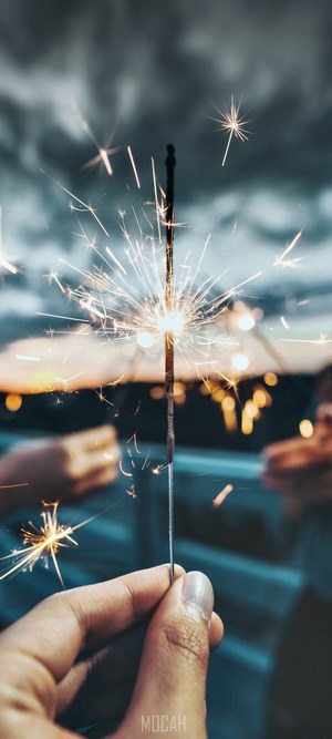 Hand holding a burning sparkler at dusk