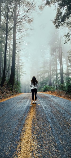 Woman standing on a foggy forest road