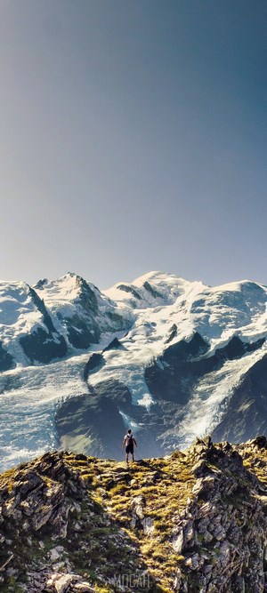 Man standing on a rocky ridge overlooking Mont Blanc mountain range