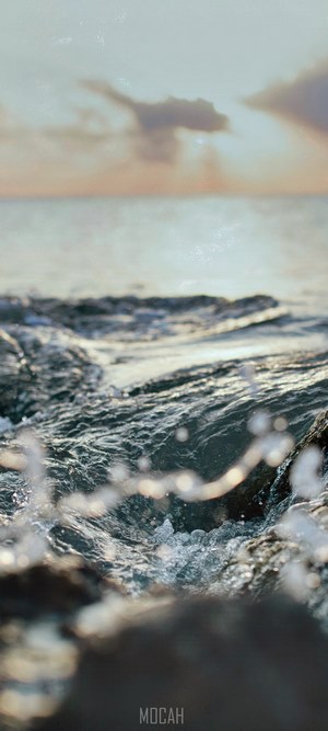 Sunrise over the ocean with waves crashing on rocks