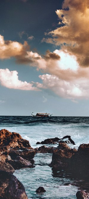 Boat on the sea with rocky shore and clouds