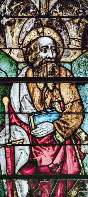 Stained glass window depicting a saint with a book and sword