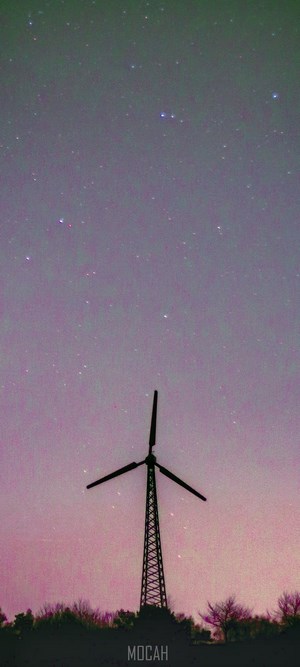Wind turbine against a starry purple and pink night sky
