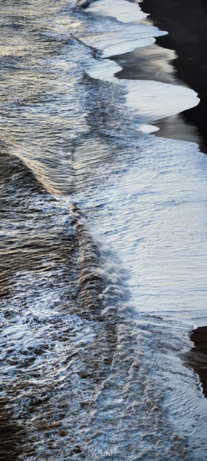 Waves crashing on black sand beach