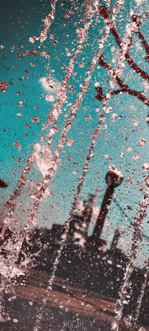 Water splashes against a teal sky with blurred background