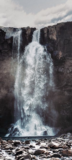 Waterfall cascading over rocky cliffs into a rocky riverbed