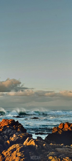 Waves crashing on rocky shore at sunset