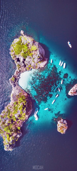 Aerial view of a tropical island with boats in turquoise water