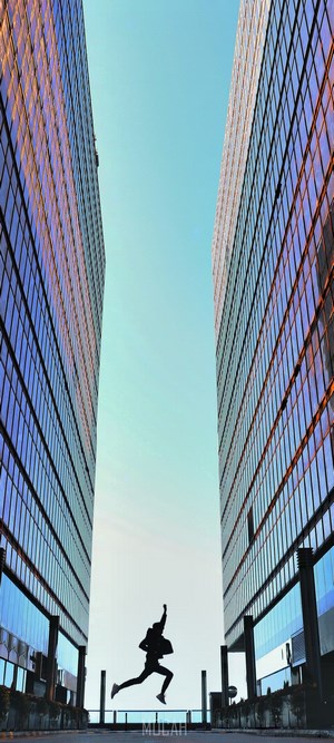 Silhouette of a person jumping between two modern buildings