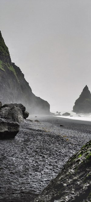 Black sand beach with rocky cliffs and ocean waves
