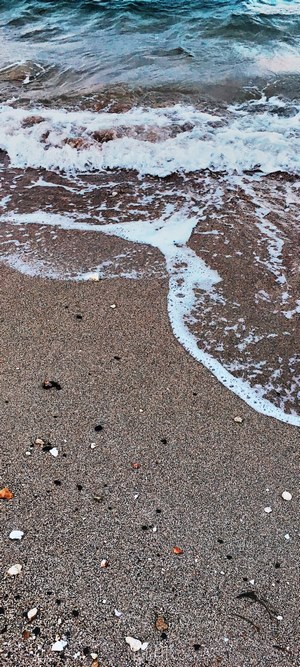Ocean waves washing over a sandy beach with pebbles
