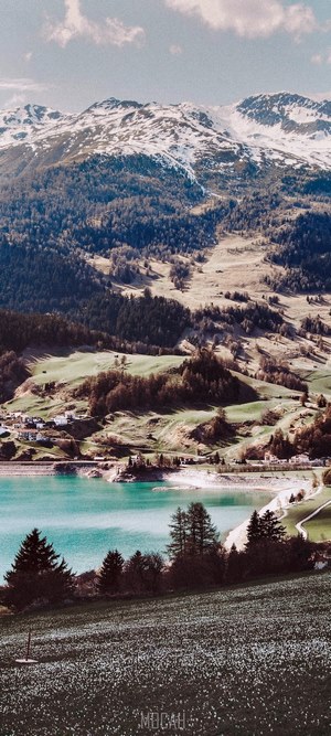 Snow-capped mountains overlooking a turquoise lake and village