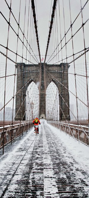 Cyclist on Brooklyn Bridge in Snow