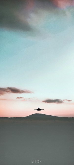 Airplane flying over a hill at sunset