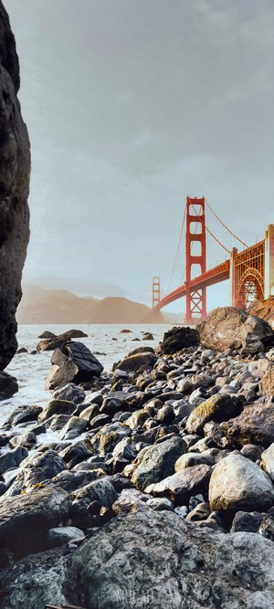 Golden Gate Bridge over water with rocky shore