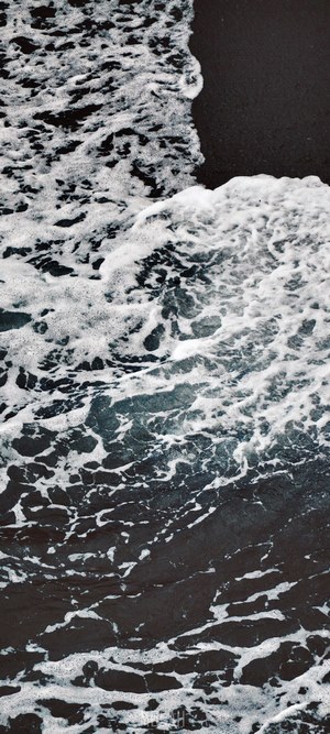 Waves crashing on a dark volcanic beach