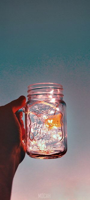 Hand Holding Light-Filled Glass Jar at Dusk