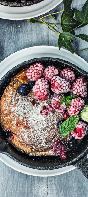Dutch baby pancake with berries in cast iron skillet