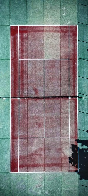 Aerial view of a red tennis court with green surroundings