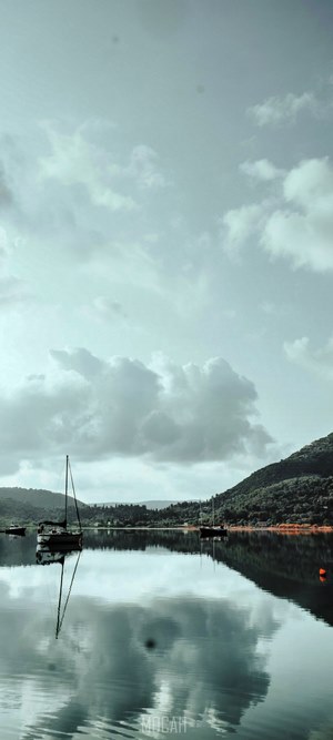 Sailboats on a calm lake with forested hills