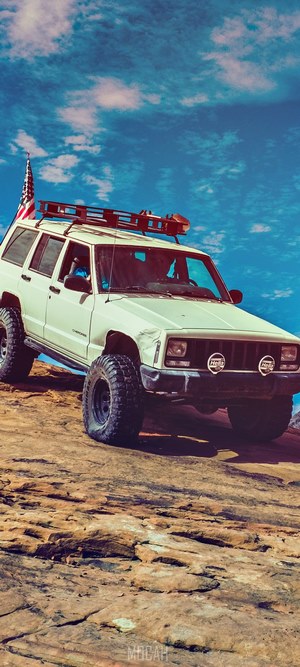 White Jeep Cherokee with American flag on roof rack