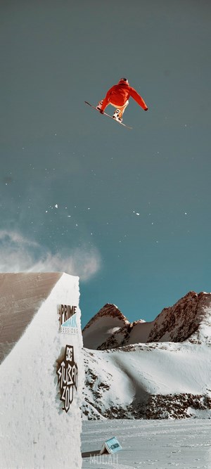 Snowboarder jumping off a snow ramp in mountains