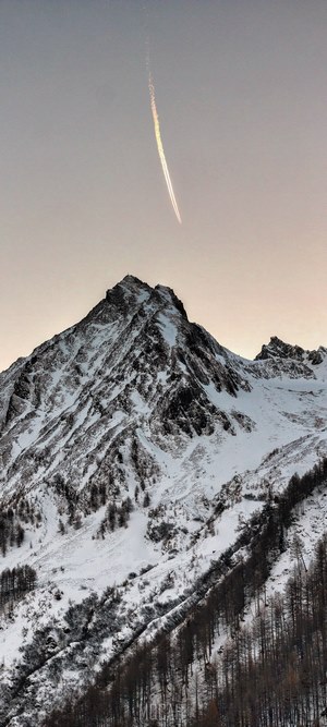 Airplane contrail over snow-covered mountain