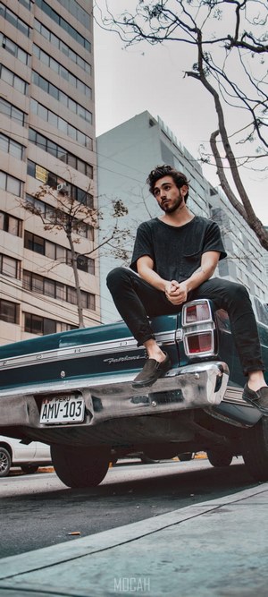 Man sitting on the trunk of a classic car