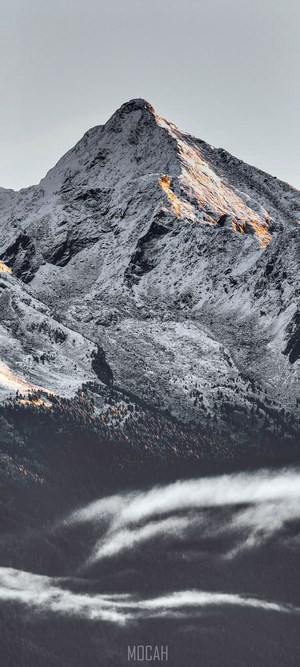 Snow-covered mountain peak with golden hour light and fog