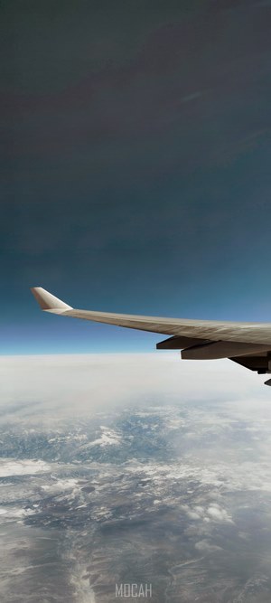 Airplane wing over clouds and land