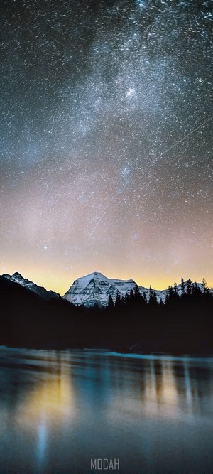 Milky Way over snow-capped mountains and lake