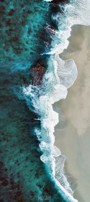 Aerial view of ocean waves crashing on a sandy beach