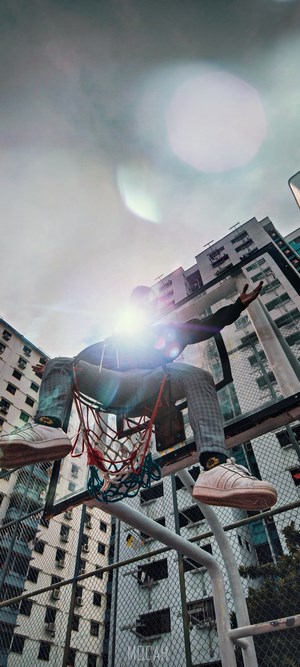 Person on basketball hoop with buildings