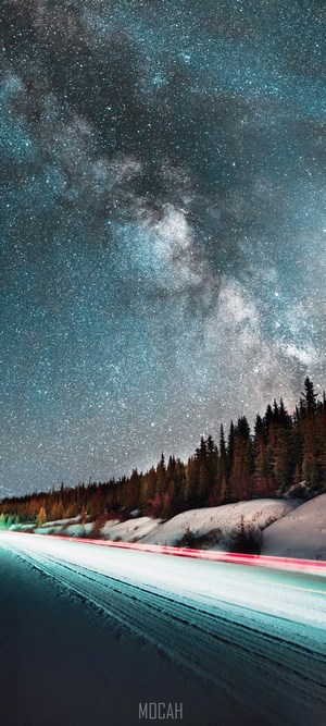 Milky Way over a snowy road with light trails