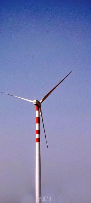 Wind turbine with red and white stripes against blue sky