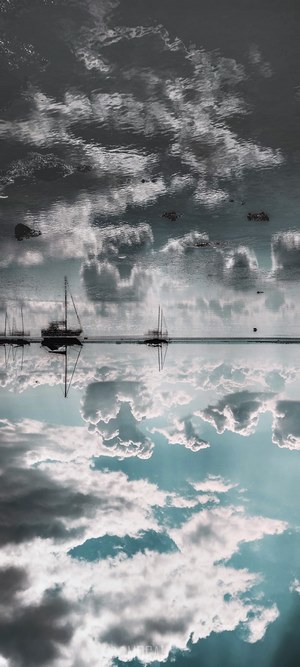 Sailboats reflected in water with clouds