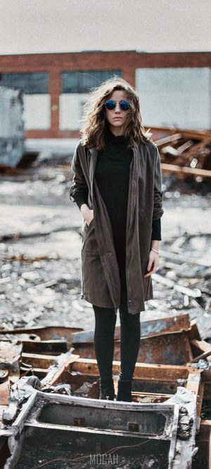Woman with curly hair and sunglasses standing in ruins