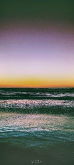 Ocean waves at sunset with purple and orange sky