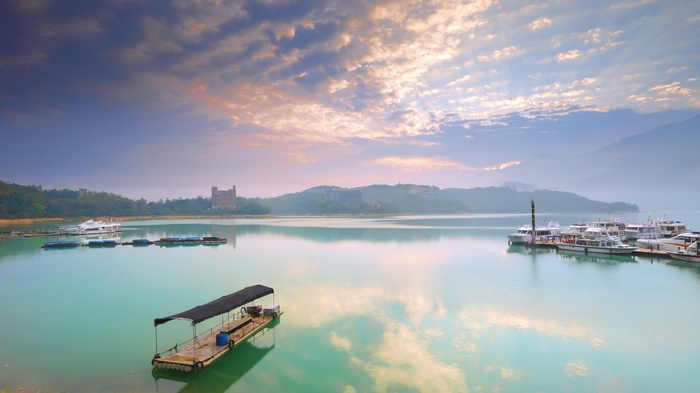 Boats on a lake with mountains and cloudy sky