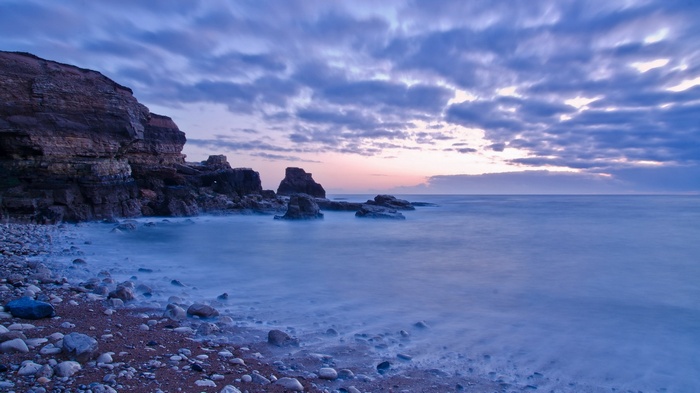 Rocky coastline with ocean waves at dusk